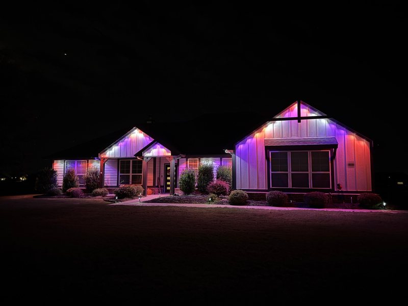 The same farmhouse lit in purple and pink for Halloween
